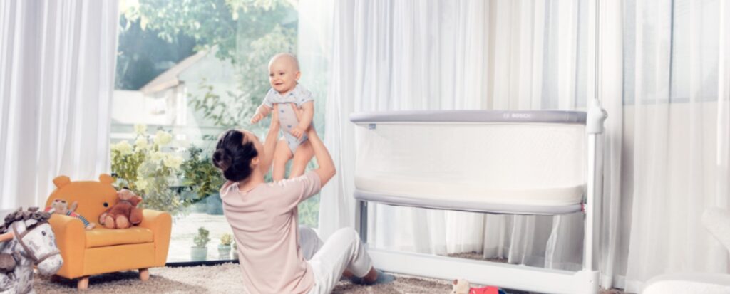 Madre levantando a su bebé en un ambiente luminoso y acogedor.
