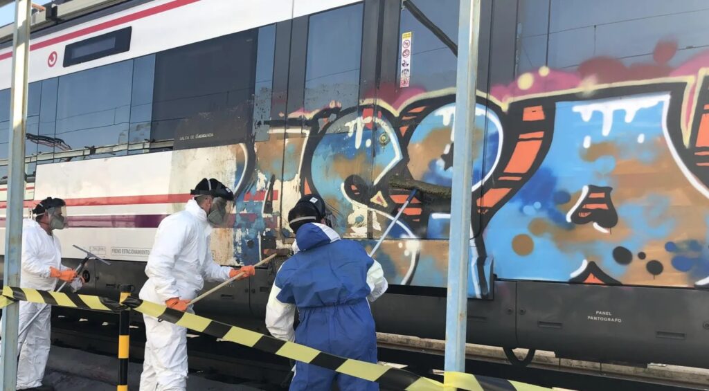 Trabajadores limpiando graffiti de un tren de Renfe