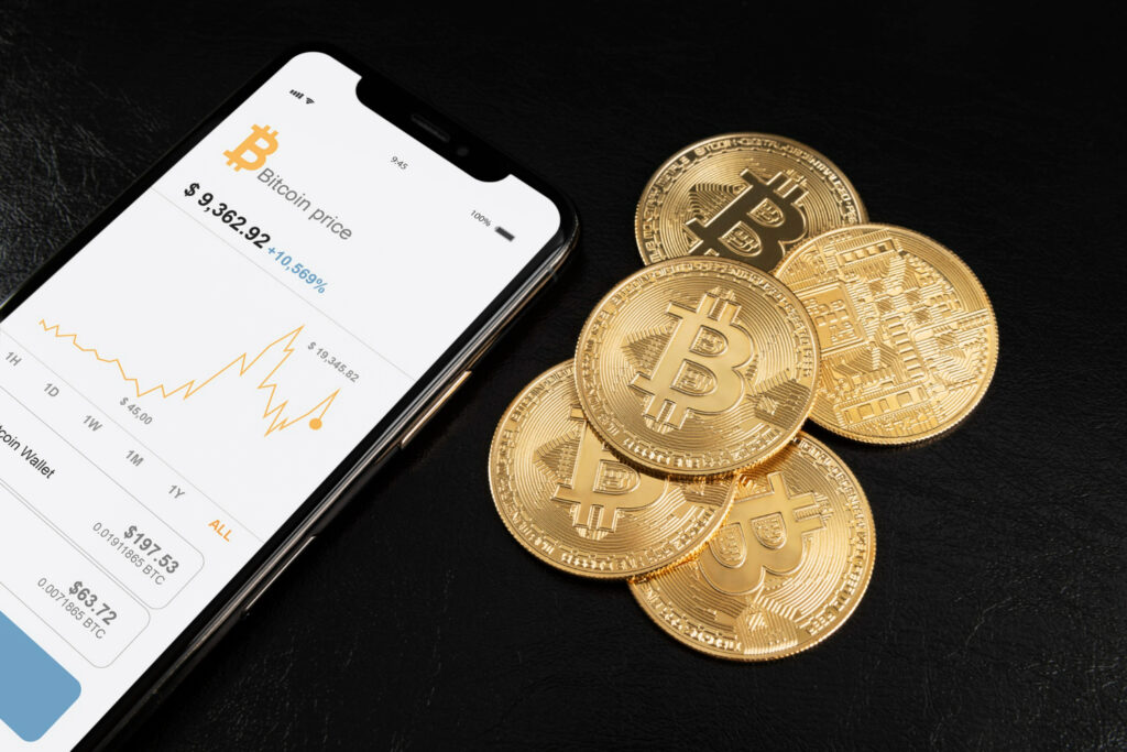 Teléfono mostrando el precio de Bitcoin junto a monedas de Bitcoin