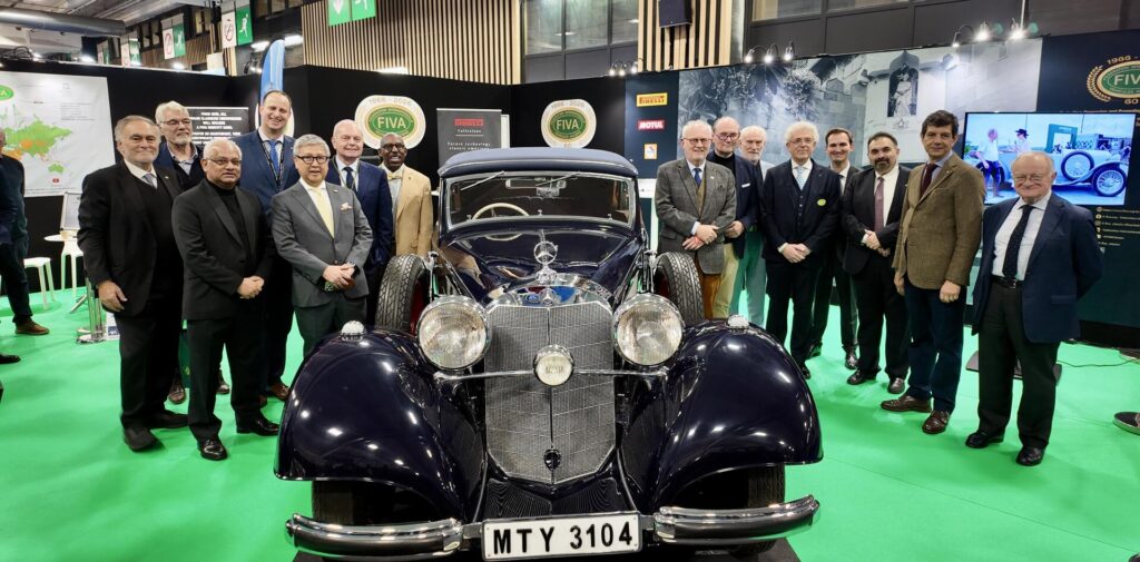 Grupo de personas en un stand de FIVA con un automóvil clásico en Retromobile Paris