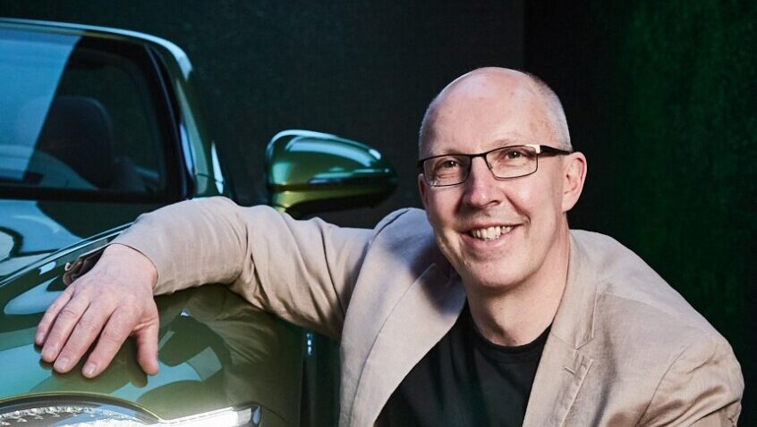 T. Jon Mayer posando junto a un coche Bentley de color verde