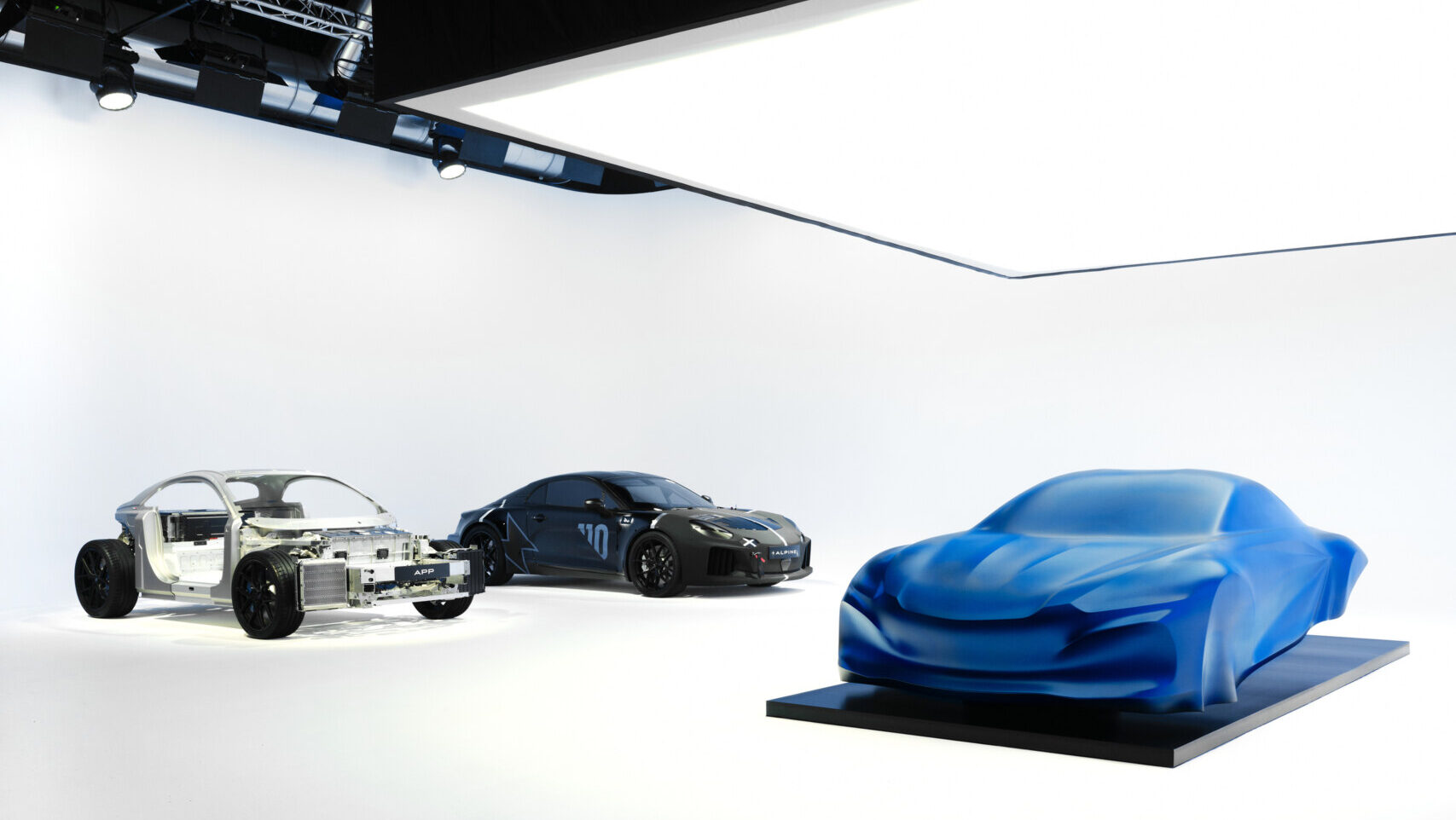 Escultura del futuro modelo Alpine A110 con velo azul en un estudio.