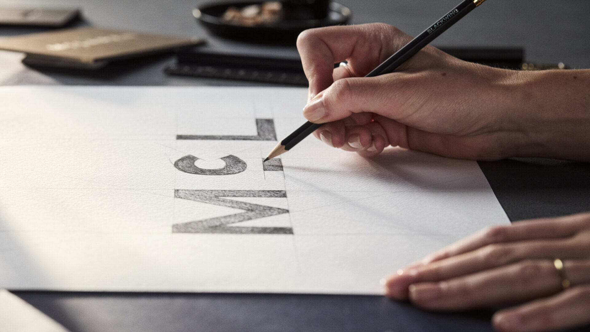 Mano dibujando el logotipo de McLaren en papel.