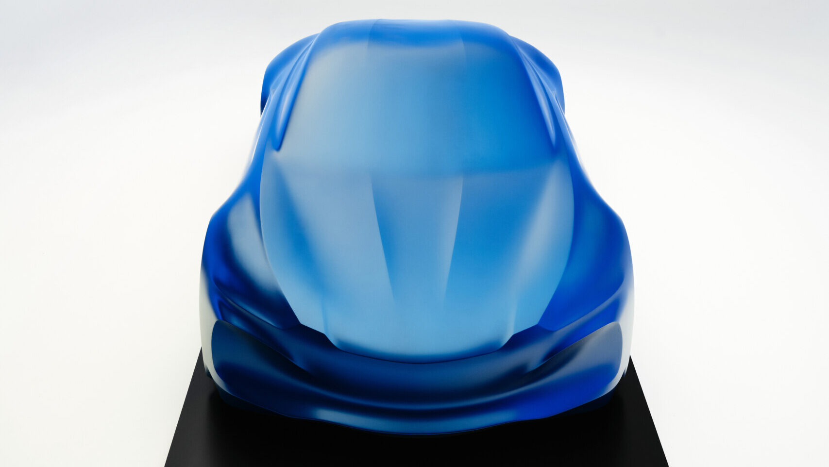 Escultura del Alpine A110 con velo azul que representa el diseño futuro.