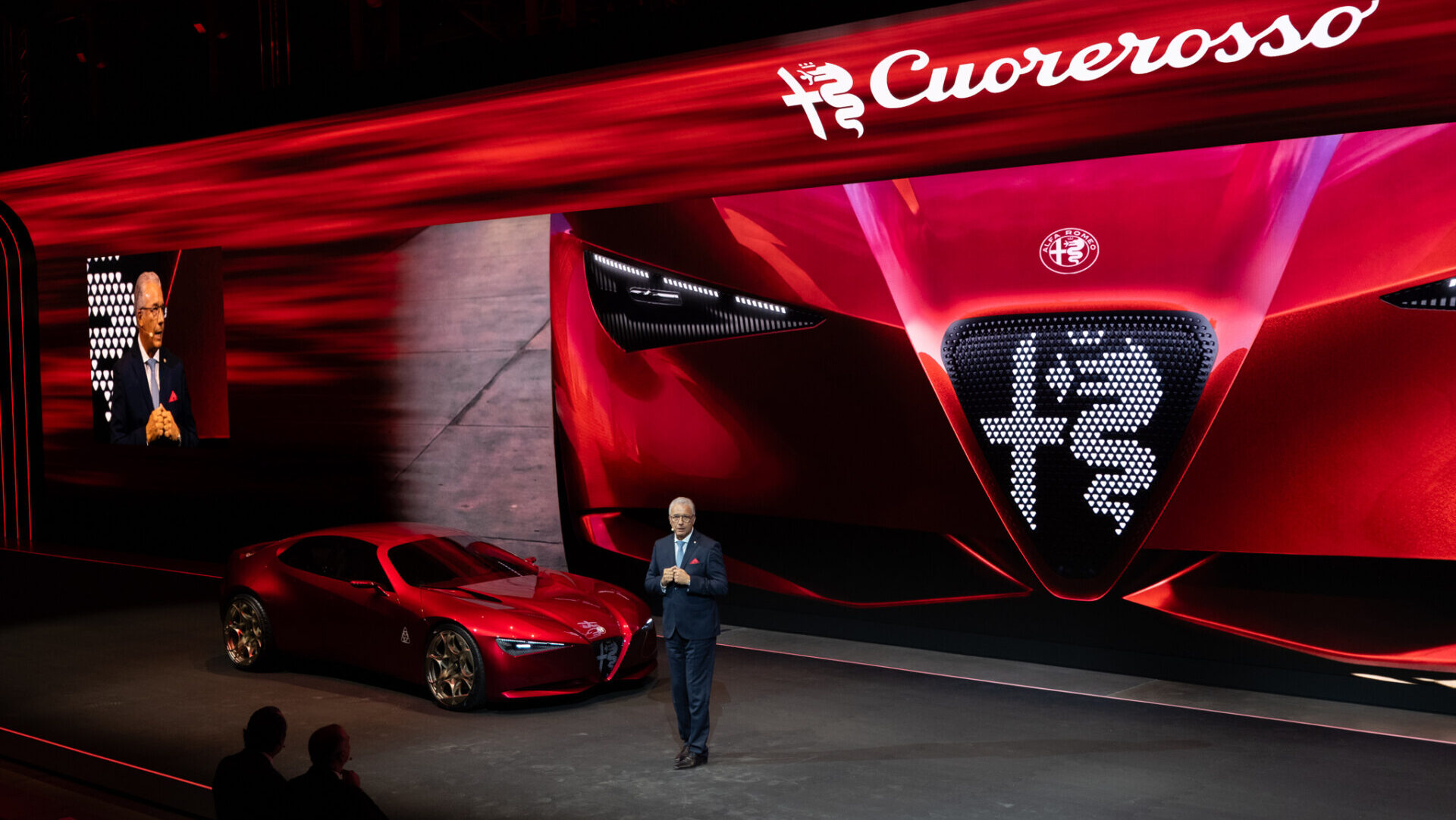 Prototipo rojo Alfa Romeo Cuorerosso en un escenario junto a un presentador.