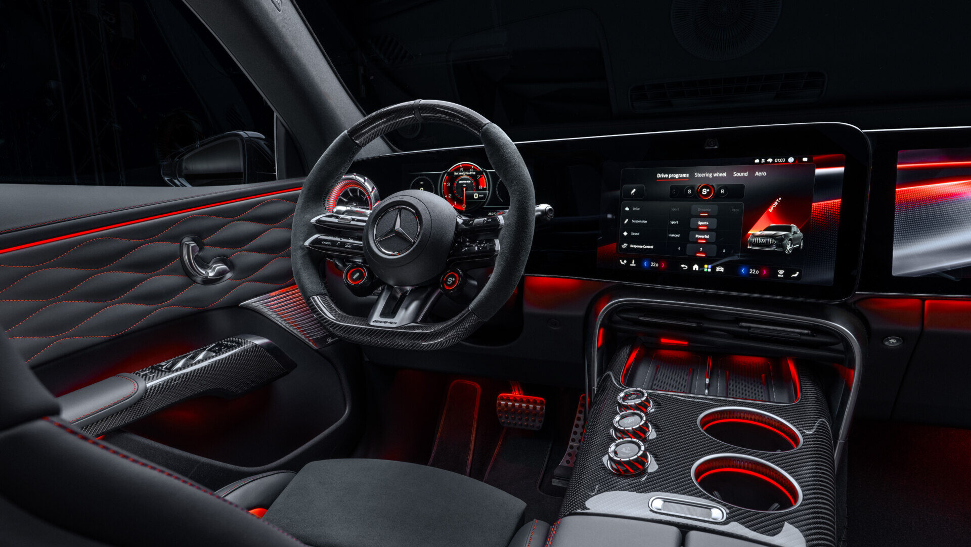 Interior de Mercedes-AMG con volante deportivo, pantallas digitales y detalles de iluminación roja