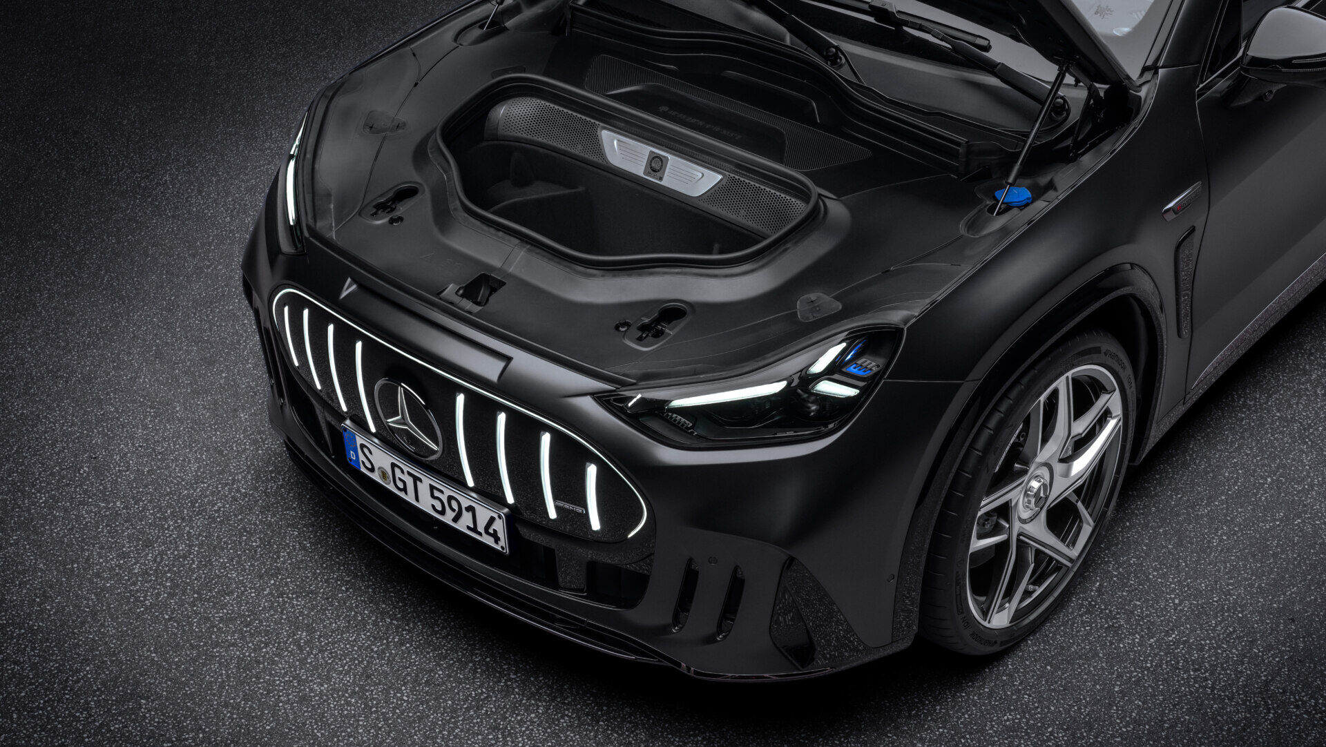 Vista elevada del frontal de un Mercedes-AMG negro con el capó delantero abierto.