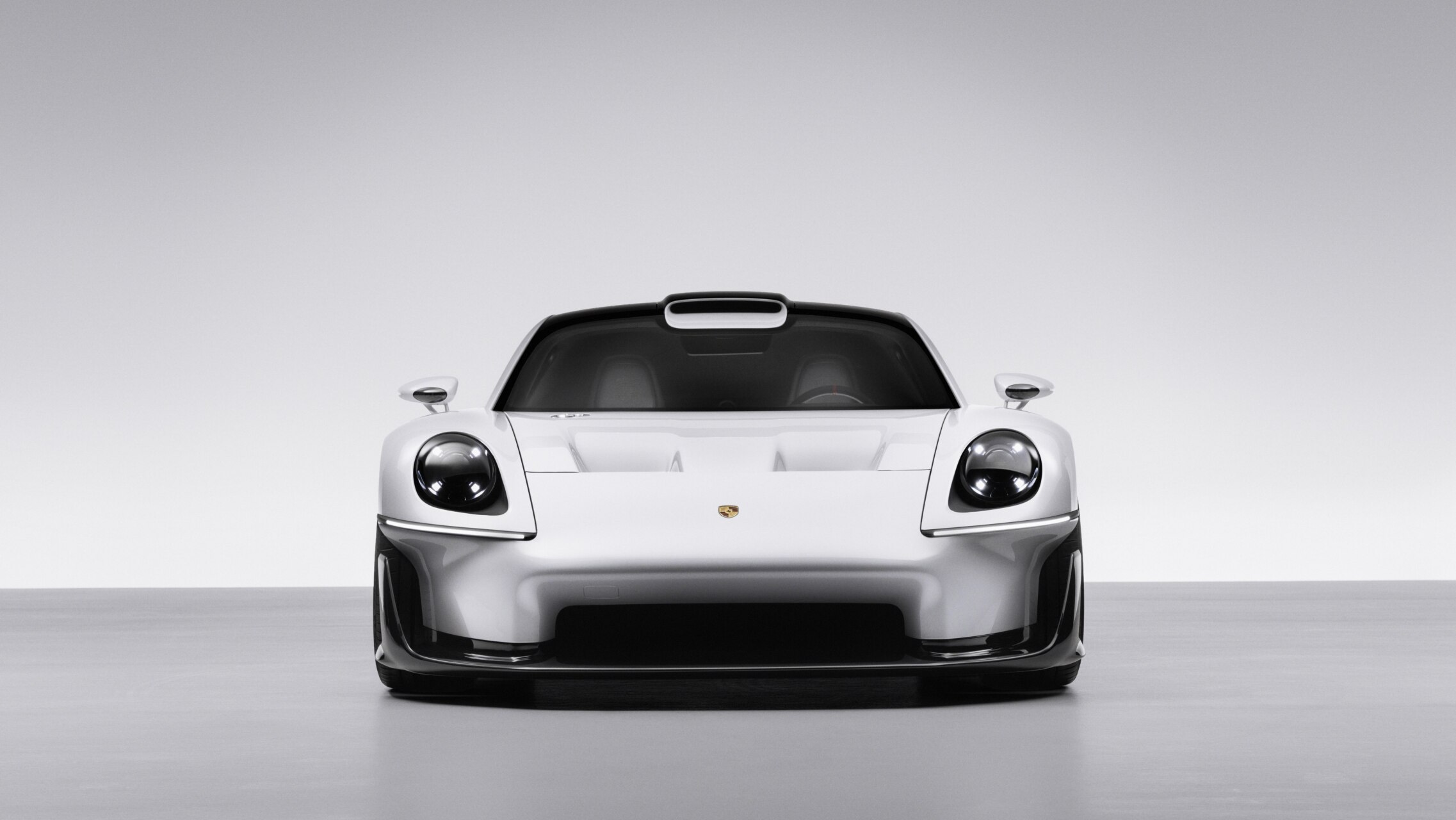 Render frontal de un deportivo blanco con faros redondos sobre fondo gris.